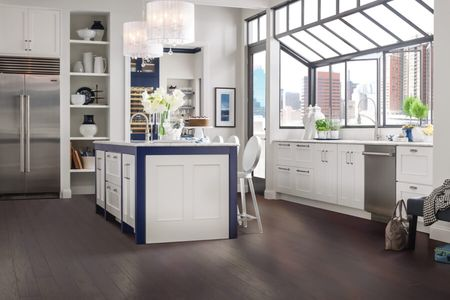 Bright contemporary kitchen with white cabinetry, a navy blue island, dark hardwood flooring.